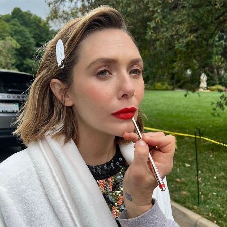 Elizabeth Olsen pouts while someone applies lipstick on her lips